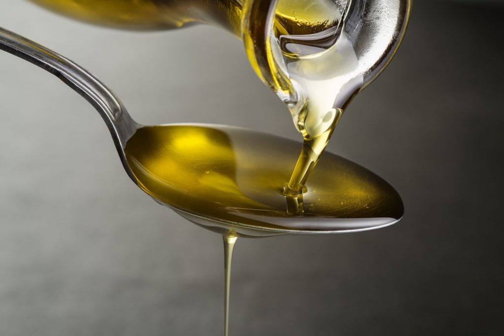 Olive oil being poured onto a spoon.